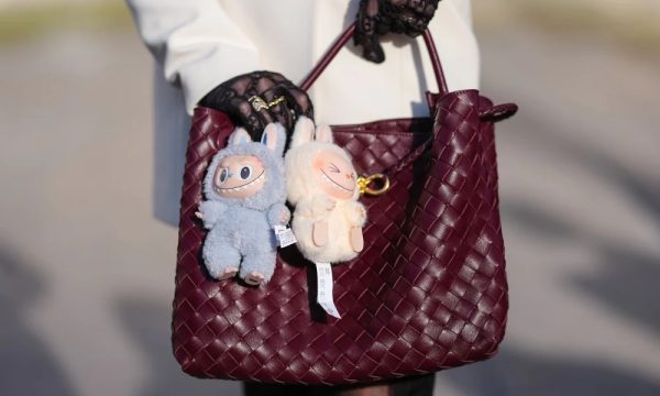 Dos muñecos Labubu colgados como charms en un bolso de diseñador burdeos, en tendencia de moda urbana 2025.