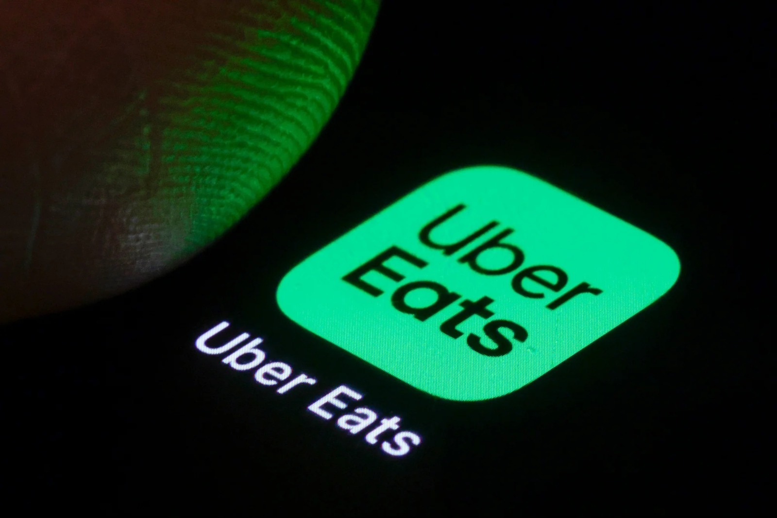 Icono iluminado de la app Uber Eats en la pantalla de un celular, representando a los trabajadores de plataformas digitales.