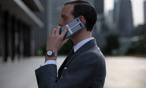 Hombre de negocios usando un smartphone Galaxy Z Flip edición especial Thom Browne en una llamada telefónica, en un entorno urbano moderno.