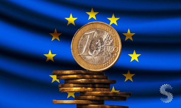 Moneda de euro frente a la bandera de la Unión Europea, ilustración sobre comercio internacional y superávit comercial en 2025.