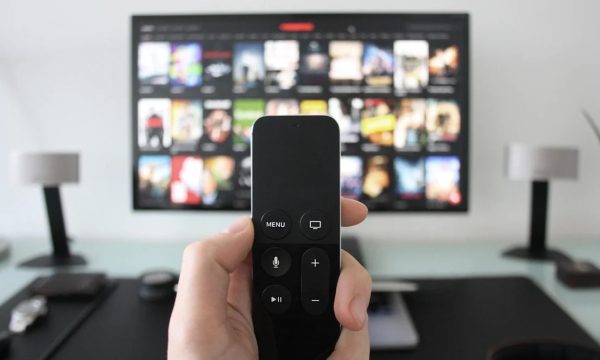 Persona usando un control remoto frente a una Smart TV con una plataforma de streaming abierta.