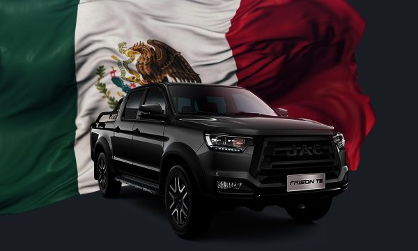 Camioneta JAC Frison T8 negra frente a una bandera de México ondeando al fondo