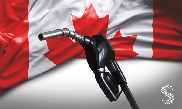 Surtidor de gasolina frente a la bandera de Canadá, en referencia a la caída de precios del combustible y su impacto en la inflación.