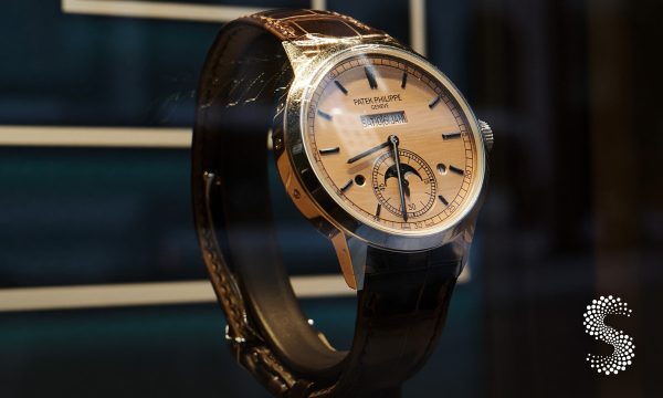 Reloj Patek Philippe de lujo en exhibición, modelo clásico suizo con correa de cuero y carátula beige.