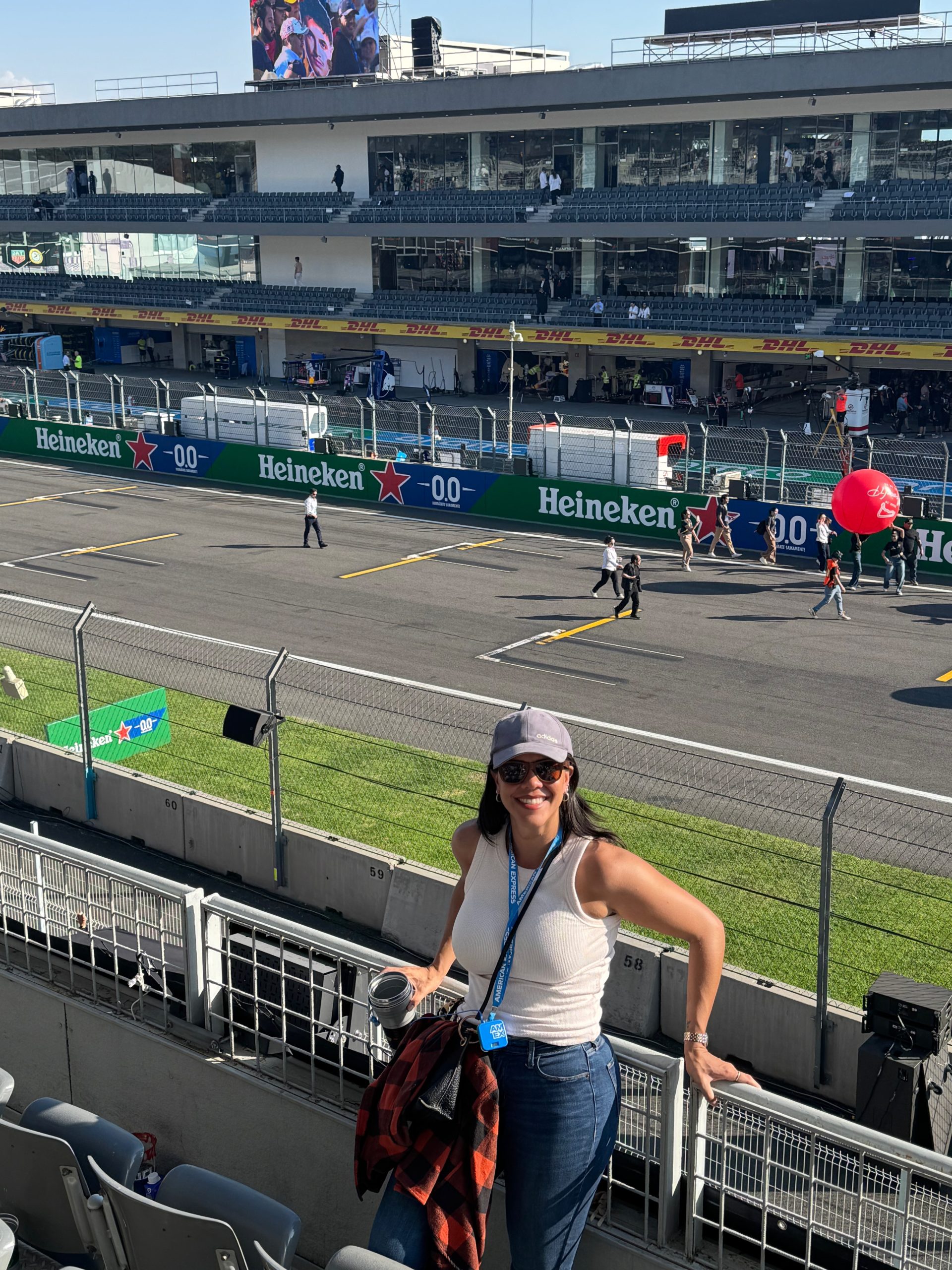 Asistente disfruta del Gran Premio de México 2025 en el Autódromo Hermanos Rodríguez, con vista a la pista y los boxes.