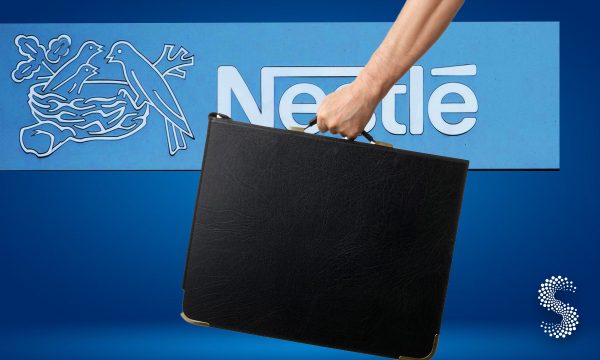 Mano sosteniendo un maletín frente al logotipo de Nestlé, simbolizando la salida de empleados tras el anuncio de despidos.